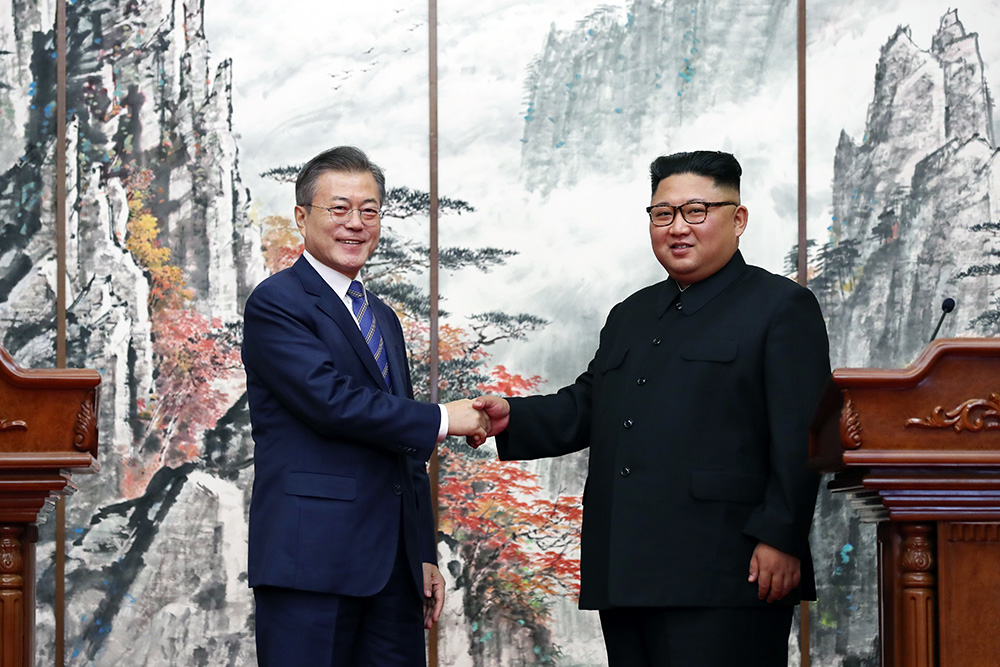 18年9月19日、平壌共同宣言を発表後に握手する南北首脳。写真は共同取材団。